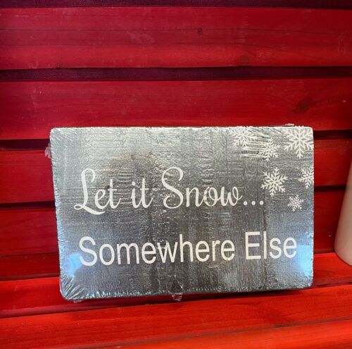 Wooden sign painted dark grey with white snowflakes decorating top right hand corner. The words Let it Snow… Somewhere Else” has been stenciled in white.